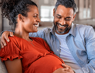 Casal com olhar satisfeito observando gravidez da mulher. Programa Gestação Segura promove a saúde das gestantes com acompanhamento durante a gravidez e no período pós-parto. Tem equipe especializada para casos de alto risco.