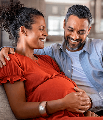 Casal com olhar satisfeito observando gravidez da mulher. Programa Gestação Segura promove a saúde das gestantes com acompanhamento durante a gravidez e no período pós-parto. Tem equipe especializada para casos de alto risco.