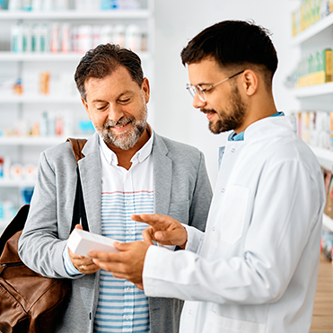 Homem consulta medicamentos com atendente farmacêutico