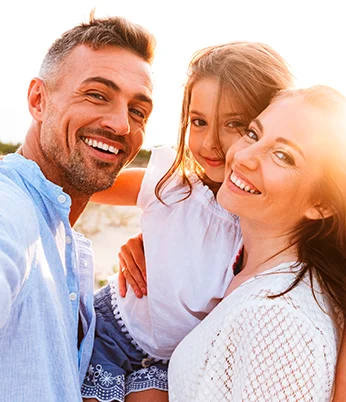 Pai, mãe e filha sorrindo, apresentando saúde bucal com planos odontológicos individuais e para empresas.