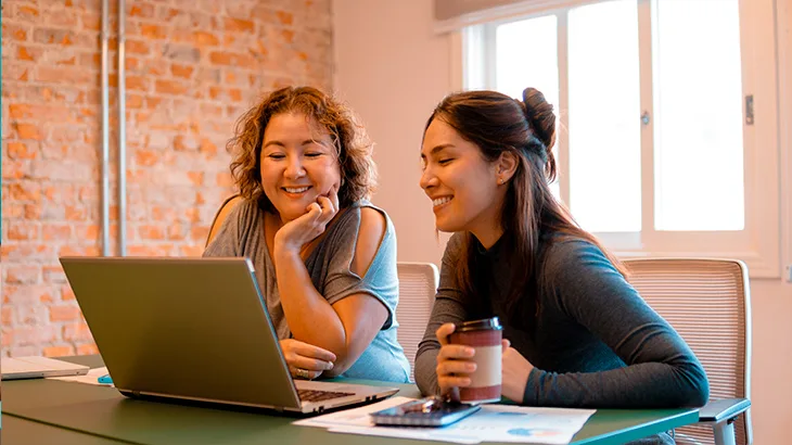 Mulheres sentadas na mesa olhando para o notebook