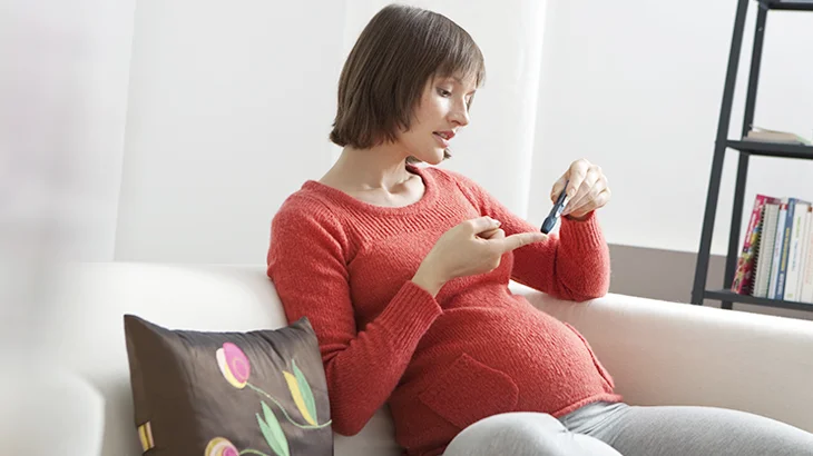 Mulher sentada no sofá, fazendo o teste da diabetes