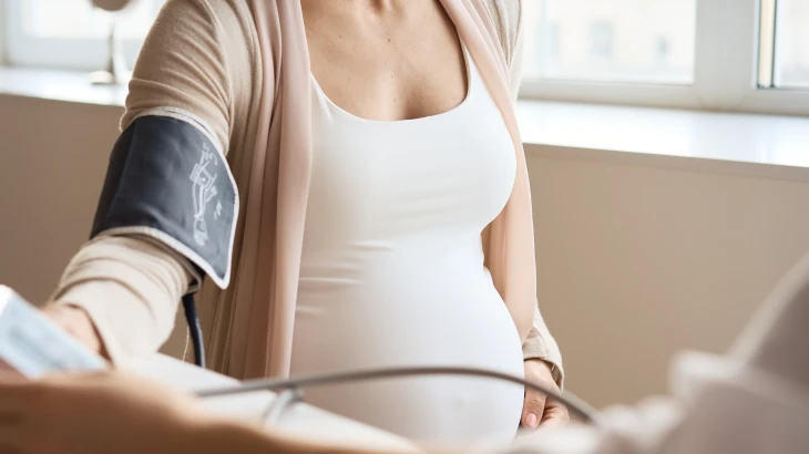 Mulher grávida com a mão na barriga medindo a pressão