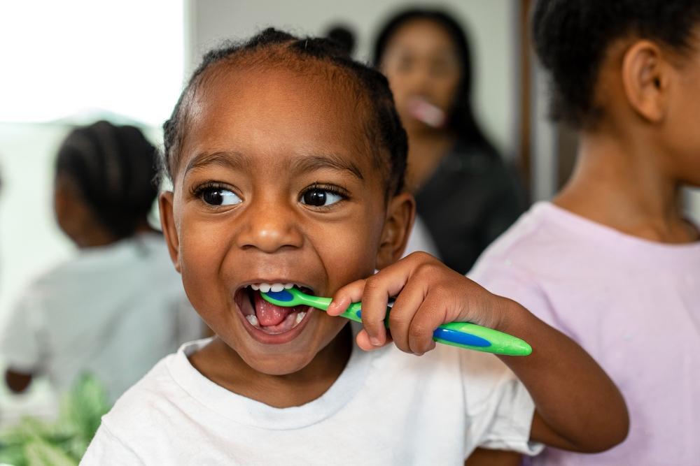 Criança escovando os dentes no banheiro, ilustrando hábitos de higiene bucal infantil e cuidados essenciais para a saúde dos dentes desde o nascimento.