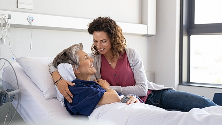 Familia se abraçando feliz no leito de um hospital.