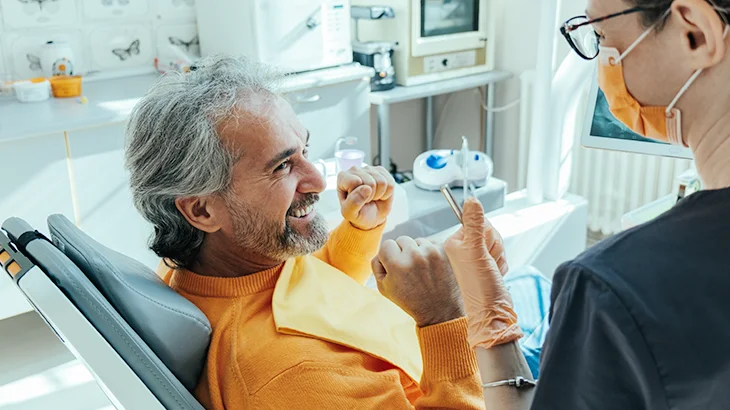 Homem sorrindo em atendimento do dentista