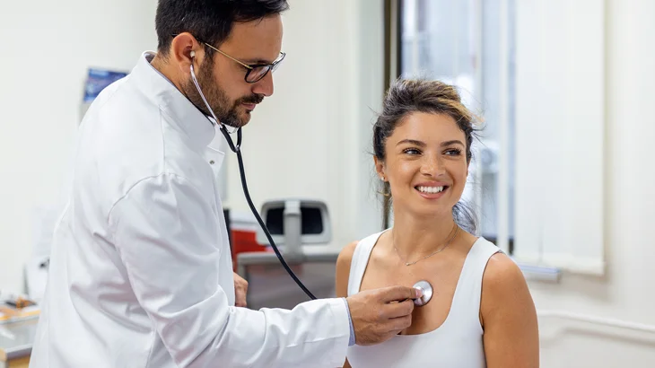 Médico com estetoscópio examinando paciente em atendimento cardiológico