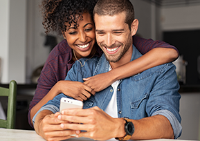 Casal abraçado olhando tela do celular