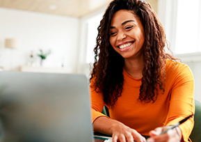 Mulher usa computador e faz anotações em caderno